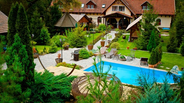 Una amplia casa con piscina, rodeada de exuberante vegetación y un jardín cuidado.