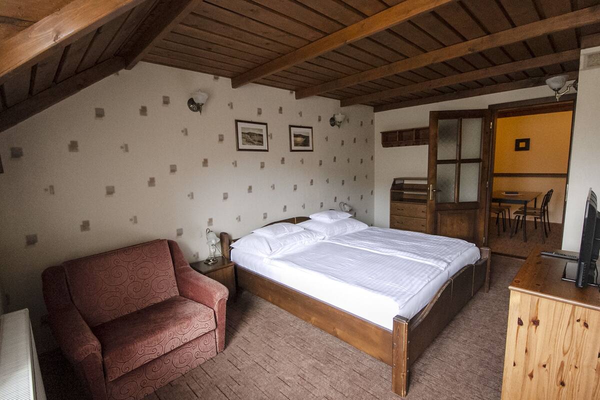 Ein Schlafzimmer mit einem Holzbett, einem roten Sofa, einer Holzkommode und einem Schreibtisch mit einem Computer.