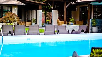A poolside area with lounge chairs and a covered seating area.