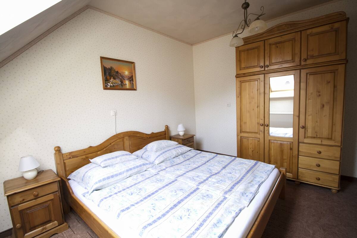 Ein Schlafzimmer mit einem hölzernen Bett, einem Nachttisch, einer Kommode und einem Bild an der Wand.