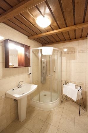 A bathroom with a glass shower enclosure, a pedestal sink, and a towel rack.