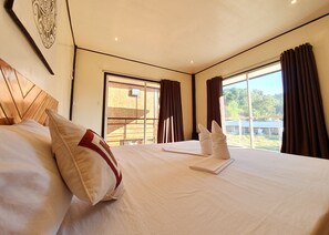 A hotel room with a large bed, a view of the outdoors, and a sliding door leading to a balcony. - Keira Tourist Inn (El Nido)