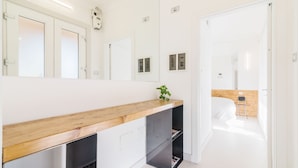 A modern bathroom with a wooden vanity, a mirror, and a small plant. - Padova - Via Ancillotto 11B (Padova)
