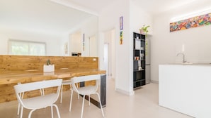 A modern kitchen with a wooden countertop, white chairs, and a black shelving unit. - Padova - Via Ancillotto 11B (Padova)