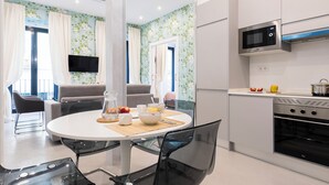 A modern kitchen with a microwave, oven, and a dining area with a round table and chairs. - Feelathome San Marcos Apartments (Madrid)