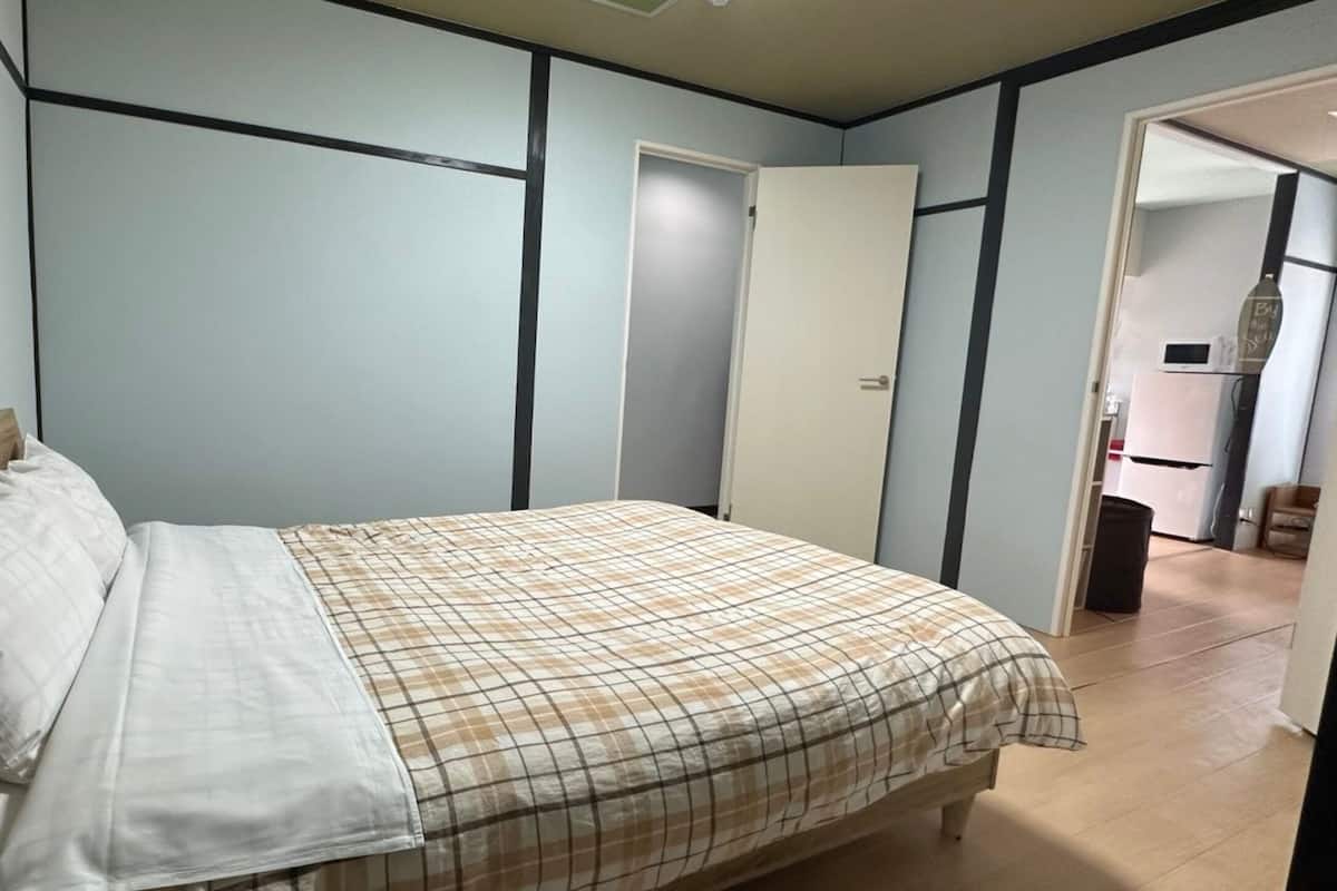 Quarto com cama, guarda-roupa e porta que dá para outro cômodo.