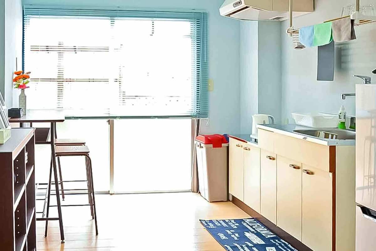 A kitchen with a refrigerator, sink, and stools.