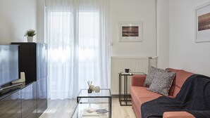 Ein modernes Wohnzimmer mit einem Glastisch, einer Couch, einem Fernseher und einer Heizung.