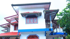 A multi-story building with traditional architectural elements, including red and blue window frames and a balcony with a railing. - Senaro Holiday Resort (Udugama)