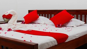 A neatly made bed with white and red bedding, a heart-shaped towel, and a vase of red flowers. - Senaro Holiday Resort (Udugama)