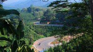 A winding road through a lush, green valley with dense foliage and a few scattered buildings. - Senaro Holiday Resort (Udugama)