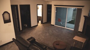 Una sala de estar con un sofá de cuero marrón oscuro, una mesita redonda y una puerta corrediza de vidrio que da a un balcón.