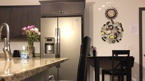Una cocina moderna con isla integrada, electrodomésticos de acero inoxidable y un comedor con mesa y sillas de madera.