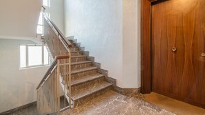 A staircase with marble steps leading to a landing, a wooden door, and a window on the landing. - Padova - Via Faggin 47A (Padova)