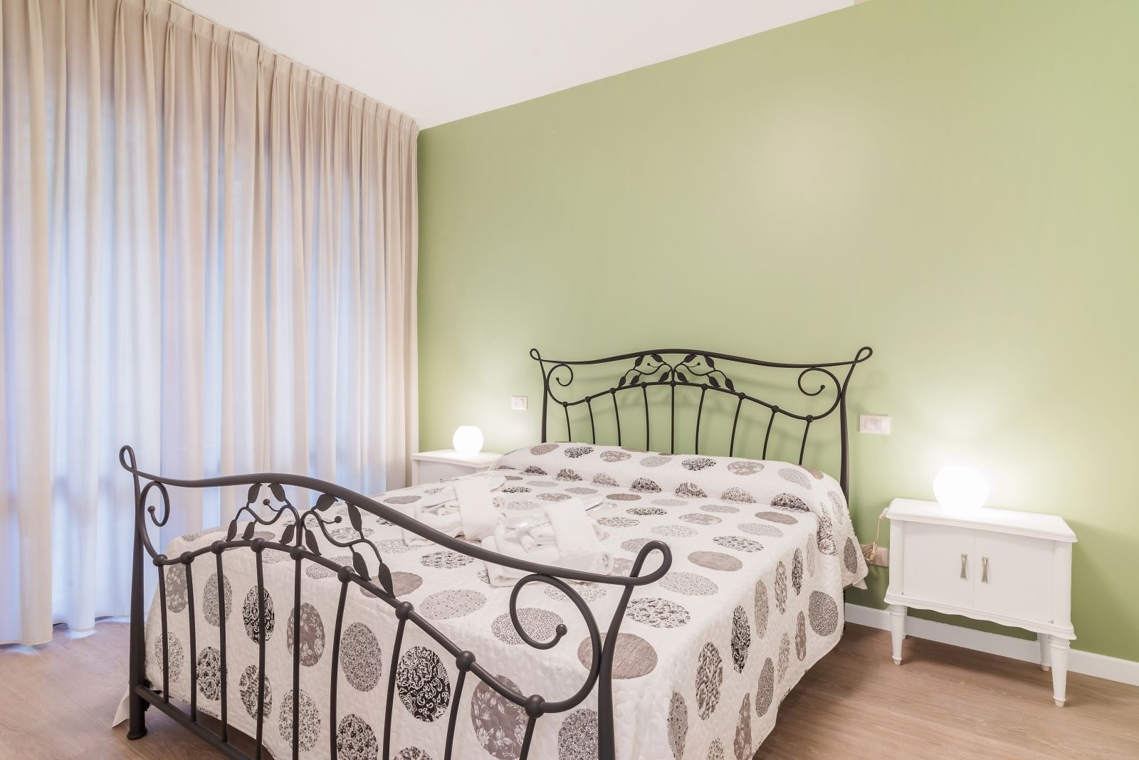 Een slaapkamer met een bed, nachtkastjes en een raam met gordijnen.