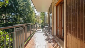A balcony with a table and chairs, a view of trees, and a tiled floor. - Padova - Via Faggin 47A (Padova)