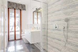 A modern bathroom with a glass shower enclosure, a white sink, and a large mirror.