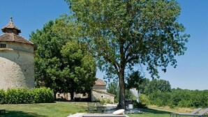 A rectangular swimming pool with clear blue water, surrounded by a well-maintained lawn and a stone building with a tiled roof. - Domaine de L'Isle Basse (Fontanes)