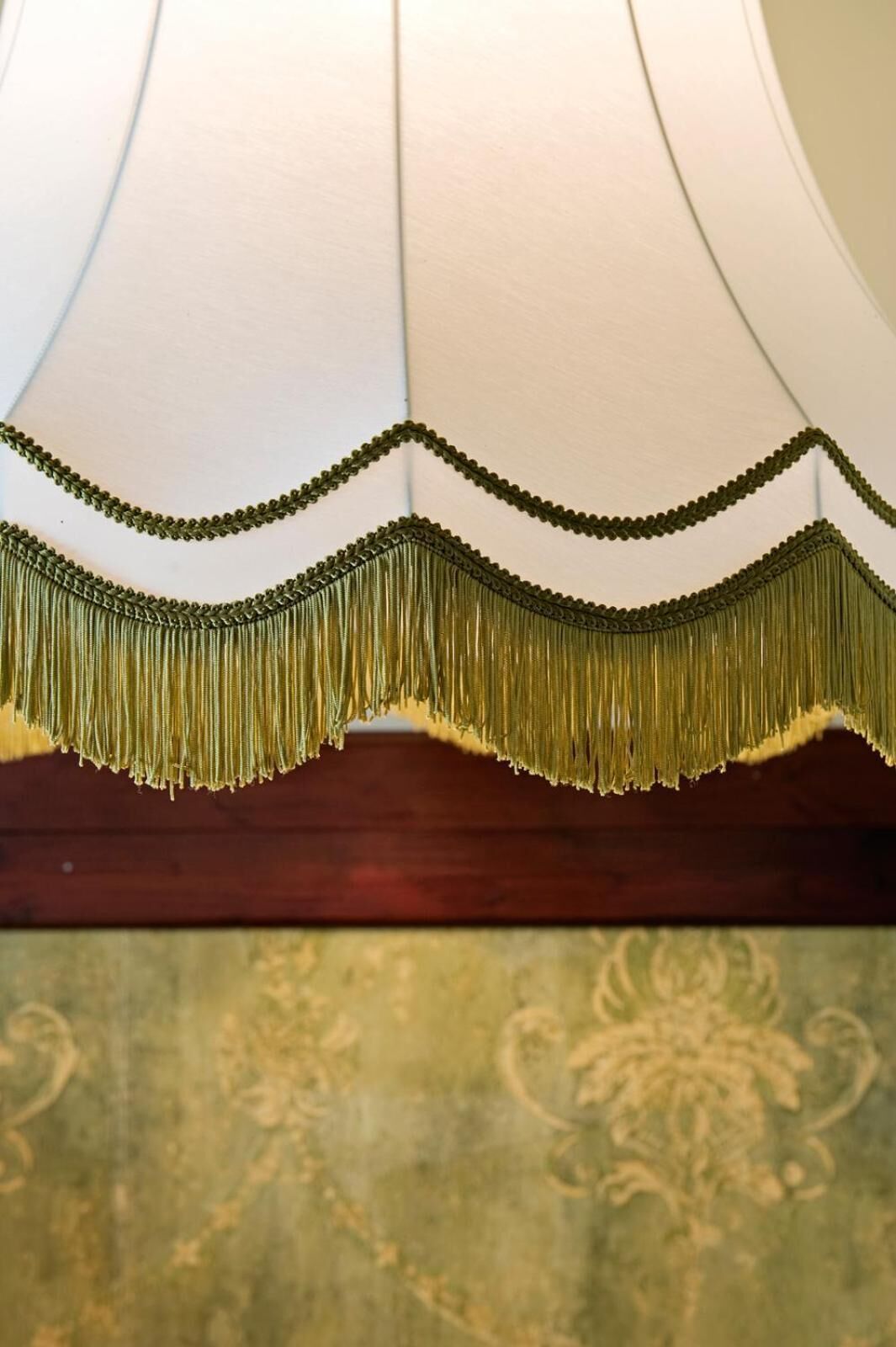 Een lamp met een decoratieve franje en een behang met patroon.