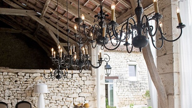 A dining area with a stone wall, a wooden ceiling, and a table set for breakfast. - Domaine de L'Isle Basse (Fontanes)