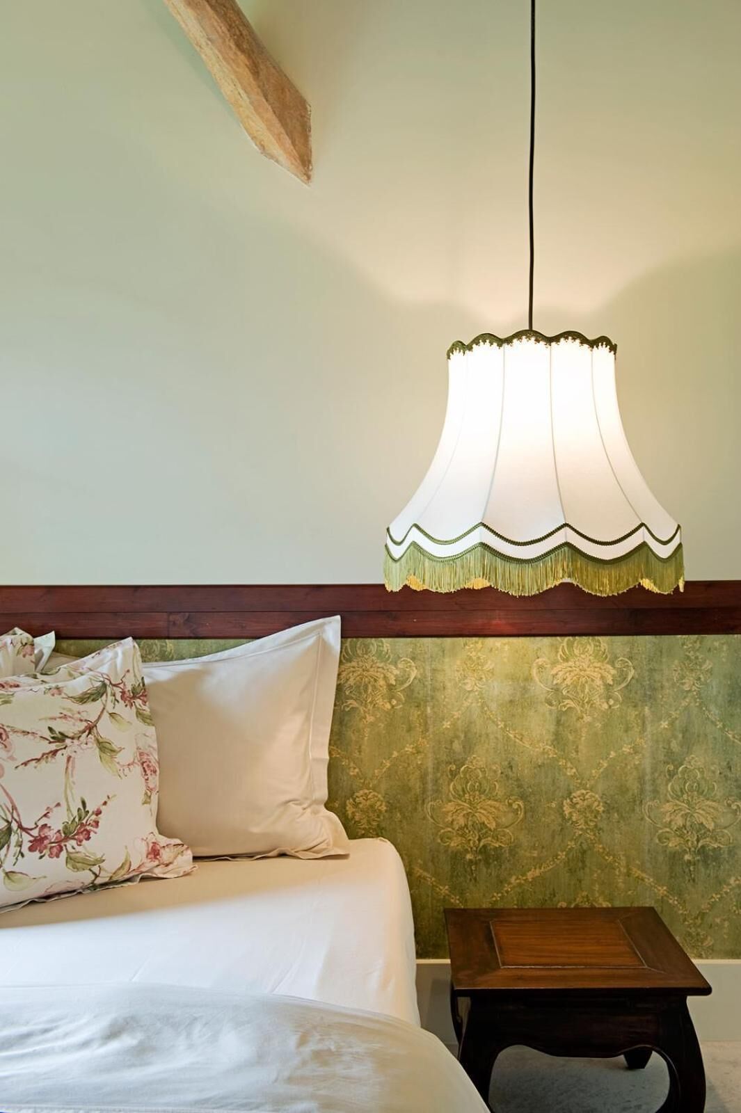 A bedroom with a bed, a nightstand, and a hanging lamp.