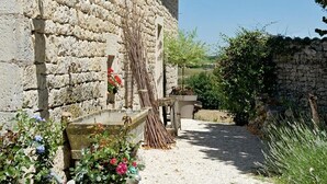 A stone building with a gravel path, potted plants, and a wooden fence. - Domaine de L'Isle Basse (Fontanes)