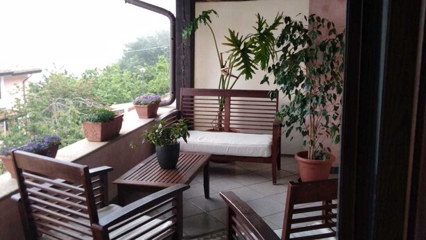 A covered outdoor seating area with wooden furniture and potted plants. - Bed & Breakfast Monti e Mare (Lanusei)