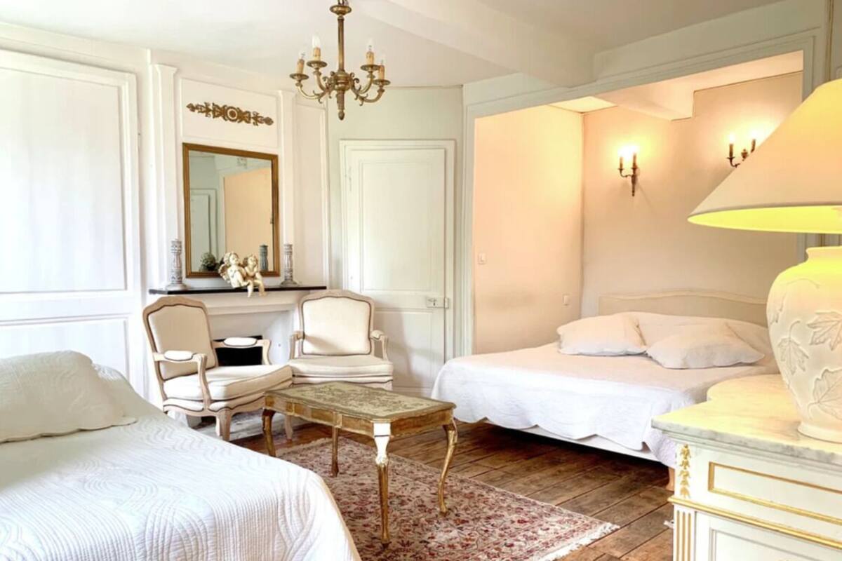 Une chambre avec deux lits, un lustre, un miroir et une lampe décorative.
