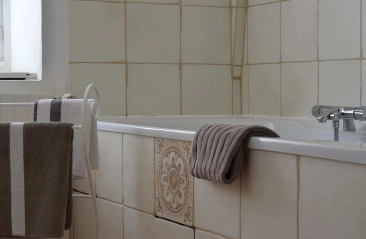 A bathroom with a bathtub, a towel rack, and a decorative tile wall.