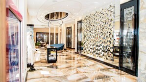 A modern hotel lobby with a marble floor, a blue sofa, and a wall of geometric mirrors. - Boutique Hotel Health Club&Spa GrandPrix (Astana)
