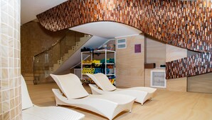 A modern spa area with two lounge chairs, a staircase, and a storage area with colorful towels. - Boutique Hotel Health Club&Spa GrandPrix (Astana)