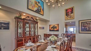 Comedor con una gran mesa de madera dispuesta para seis comensales, rodeada de sillas. A la izquierda, un aparador de madera con puertas de cristal, y un candelabro sobre la mesa.