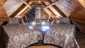 A cozy attic bedroom with a wooden ceiling, a bed with patterned bedding, and a visible skylight.