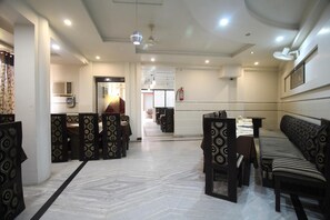 A hotel lobby with a reception desk, seating area, and a fire extinguisher on the wall. - FabHotel Alpine (Agra)