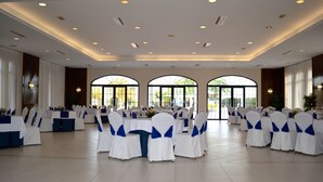 A spacious banquet hall with tables set for a formal event, featuring white and blue tablecloths and matching chair covers. - Hotel Veracruz (Don Benito)