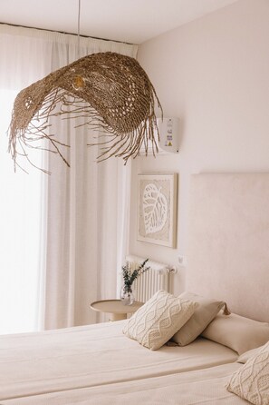 Un dormitorio con una cama, un colgante de luz, un radiador y una obra de arte enmarcada en la pared.