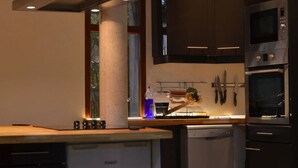 A modern kitchen with dark cabinets, stainless steel appliances, and a window providing natural light. - La Villa dans les Pins (Quend)