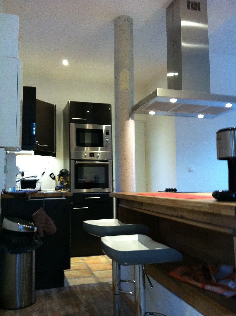 A modern kitchen with stainless steel appliances, a central island, and bar stools.