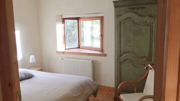 Une chambre à coucher avec un lit, une chaise, un radiateur et une fenêtre donnant sur des arbres.