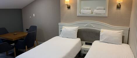A hotel room with two single beds, a small table, and two chairs.