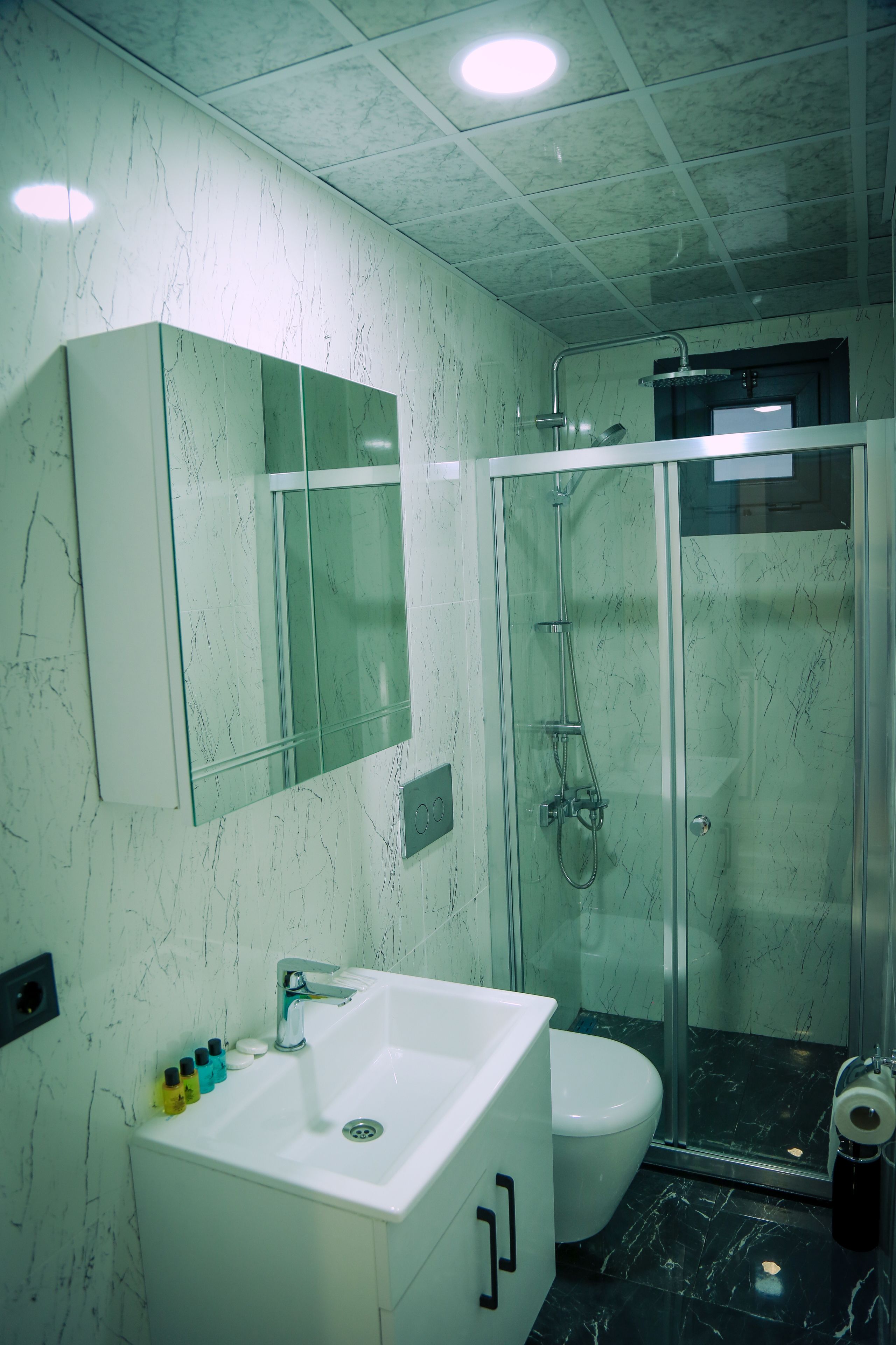 Ein Badezimmer mit einem weißen Waschbecken, einer Toilette und einer Duschkabine.
