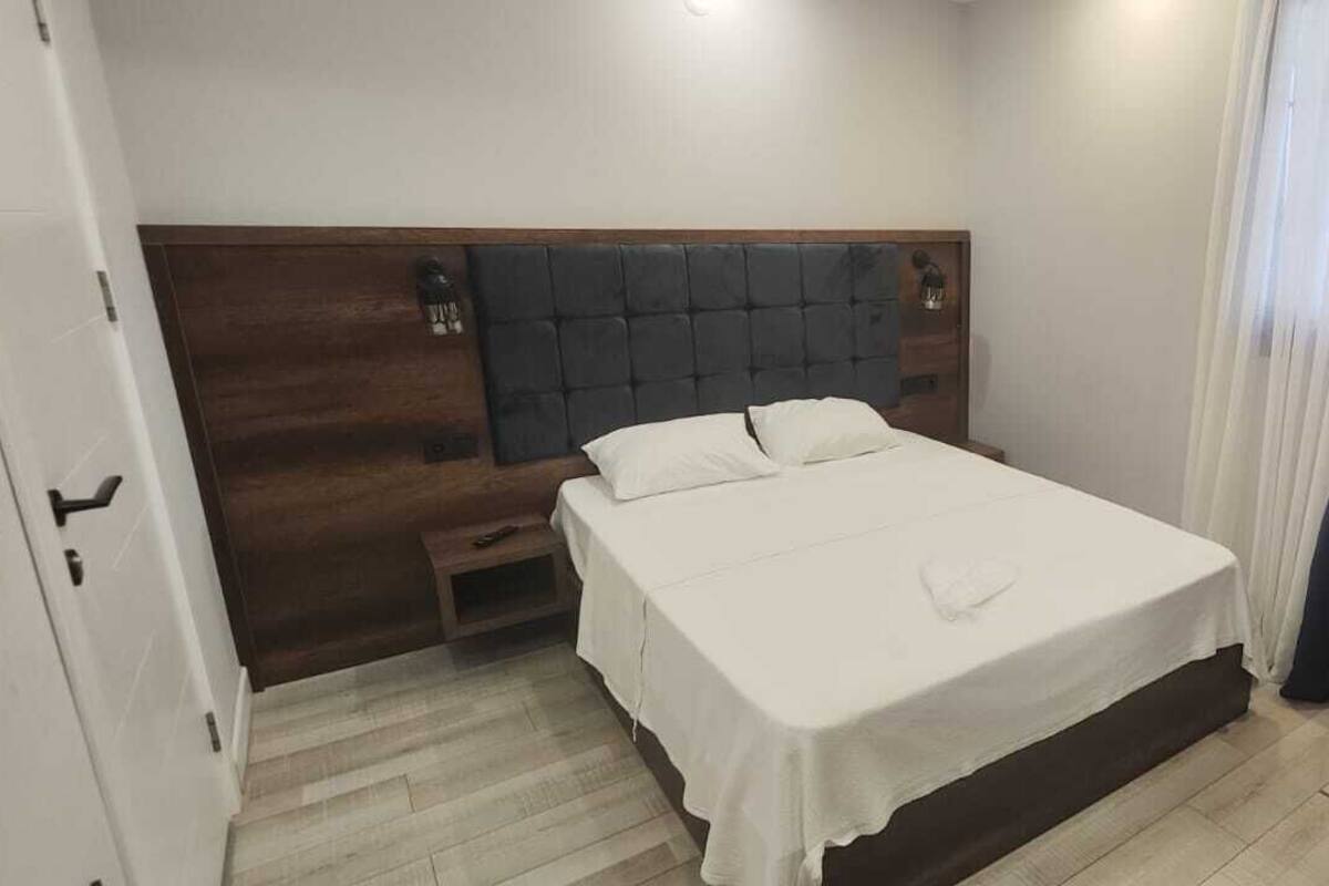 A bedroom with a bed, a nightstand, and a wooden headboard.