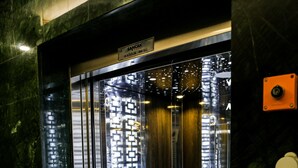 An elevator interior with a glass door, a phone, and a digital display. - White Golden Suite Hotel (Trabzon)