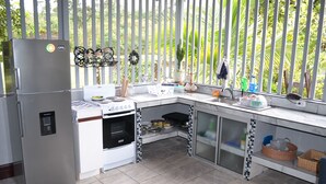 A kitchen with a refrigerator, oven, and sink. There is a window with a view of greenery outside. - Rent 1 apt for up to 6 guests or both apartments for 12 guests and a discount (Guapiles)