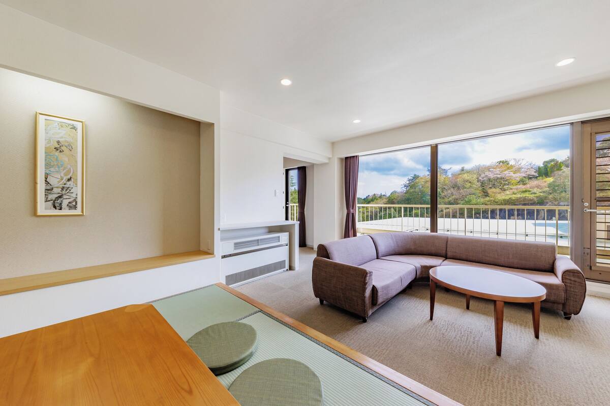 A modern living room with a sectional sofa, a round coffee table, and a view of the outdoors.