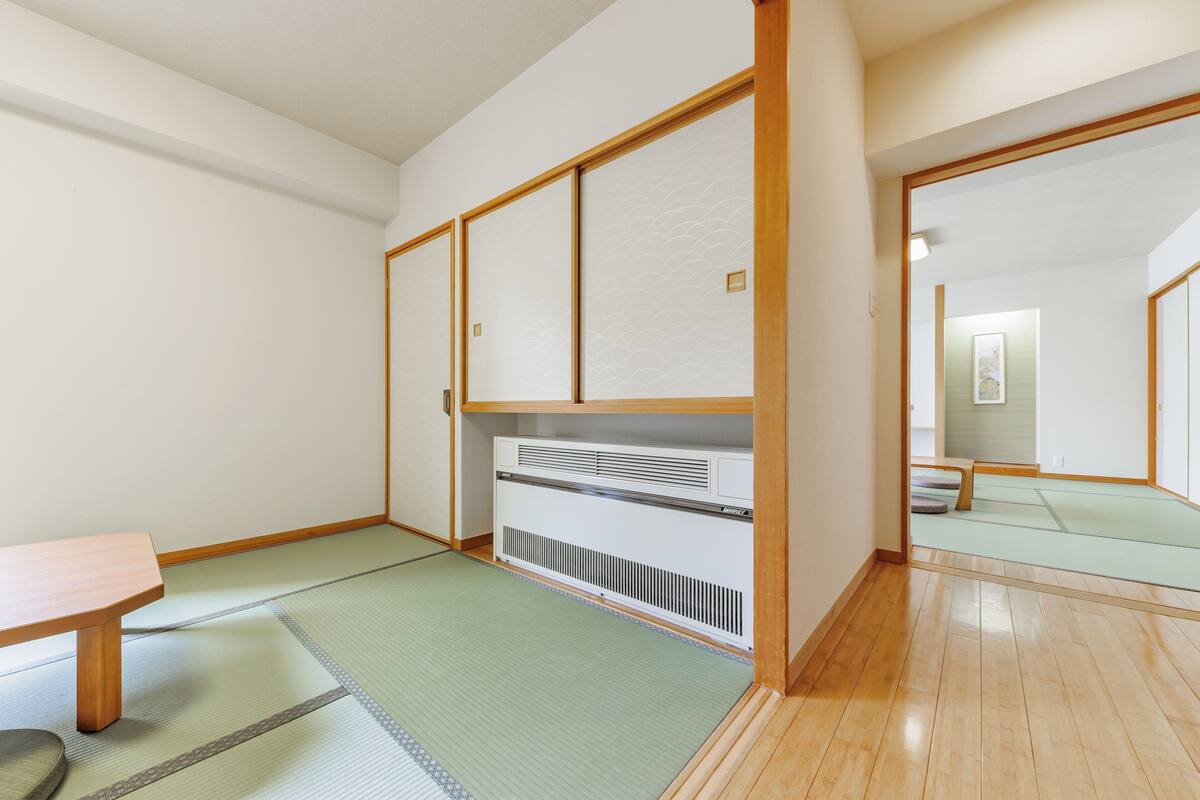 A traditional Japanese room with tatami flooring, sliding doors, and a built-in heater.