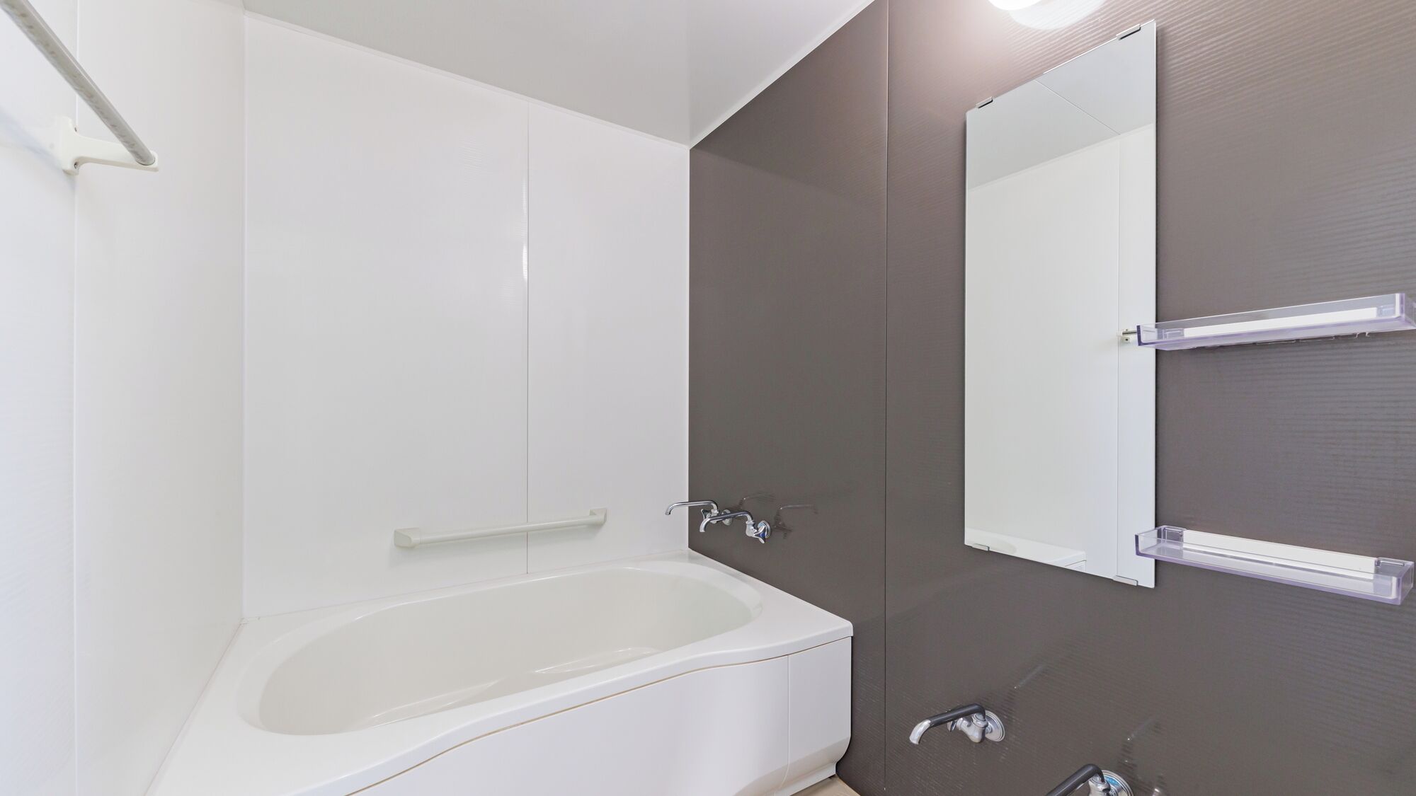A modern bathroom with a bathtub, a large mirror, and a shower area.