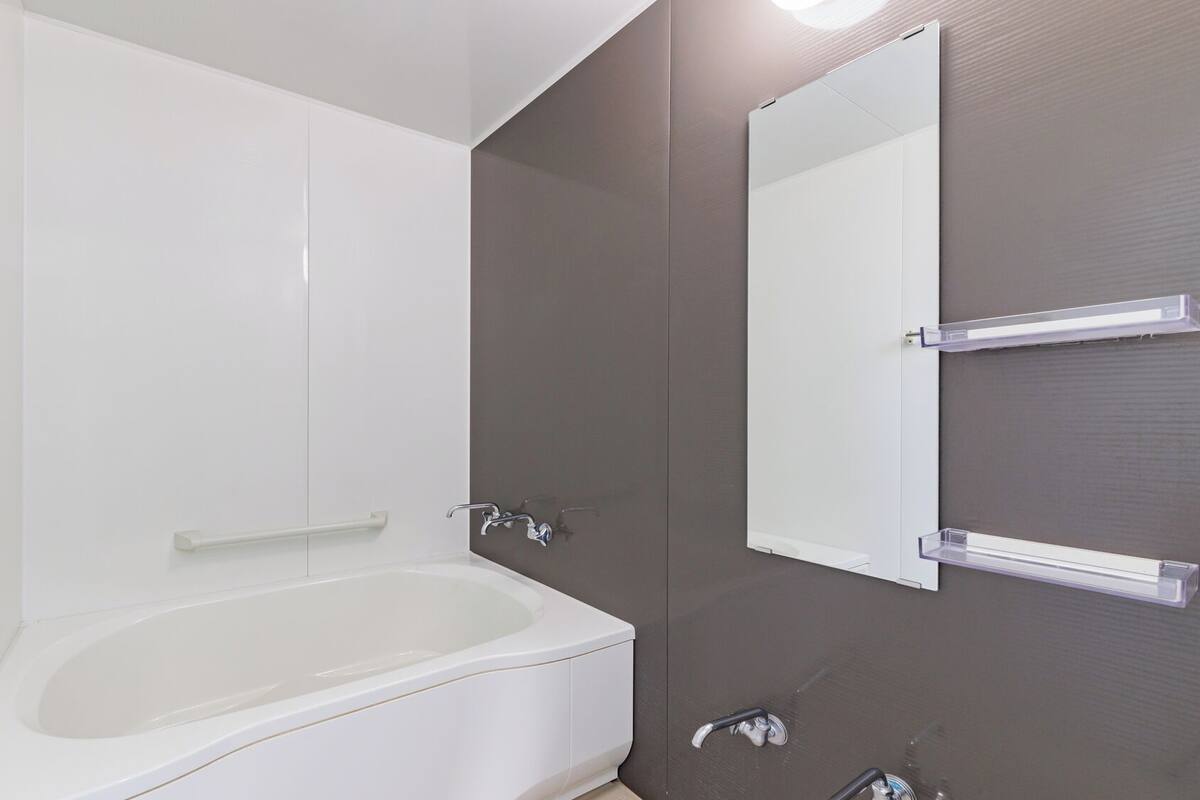 A modern bathroom with a bathtub, a large mirror, and a shower area.