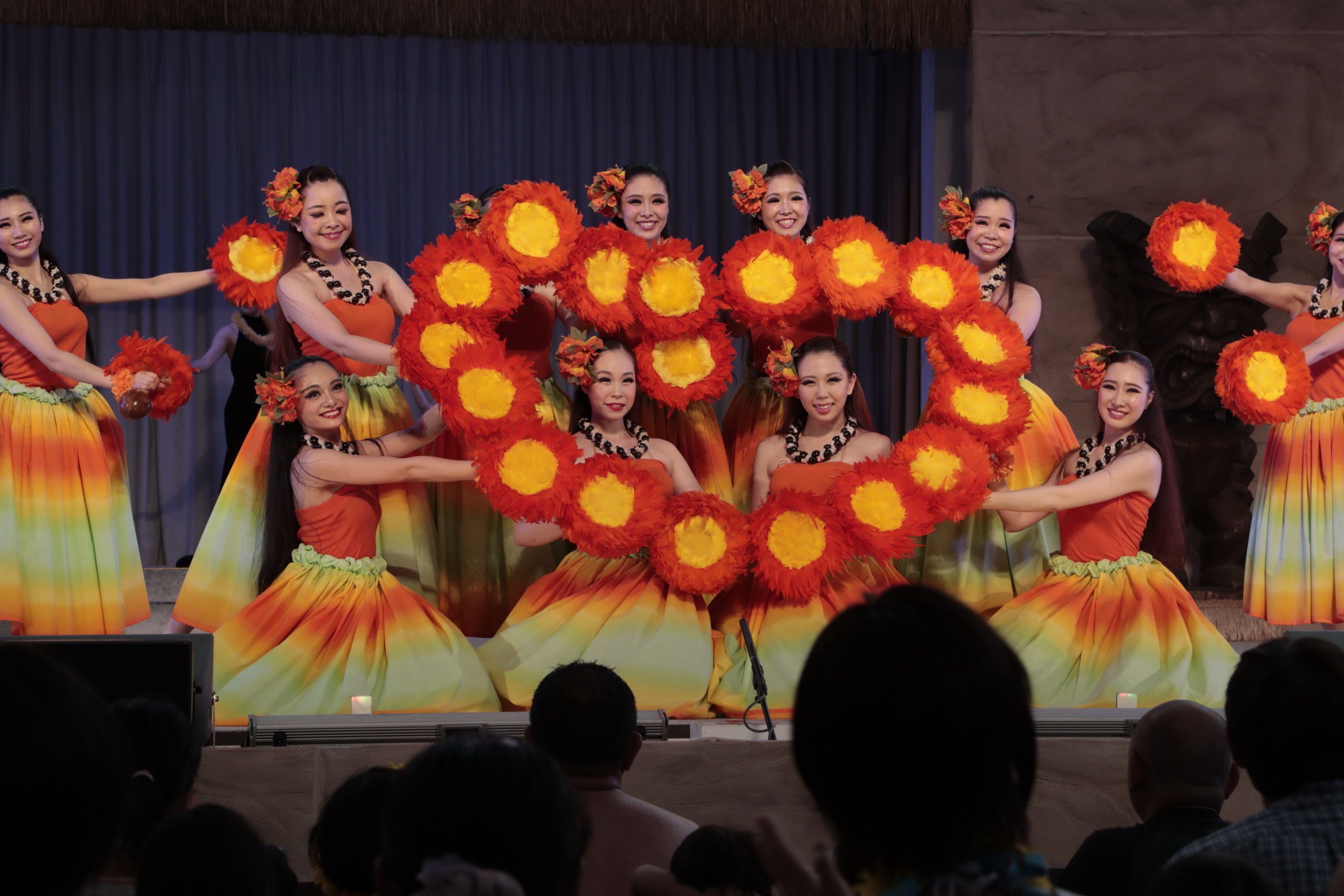 A group of performers on stage with colorful costumes and props.
