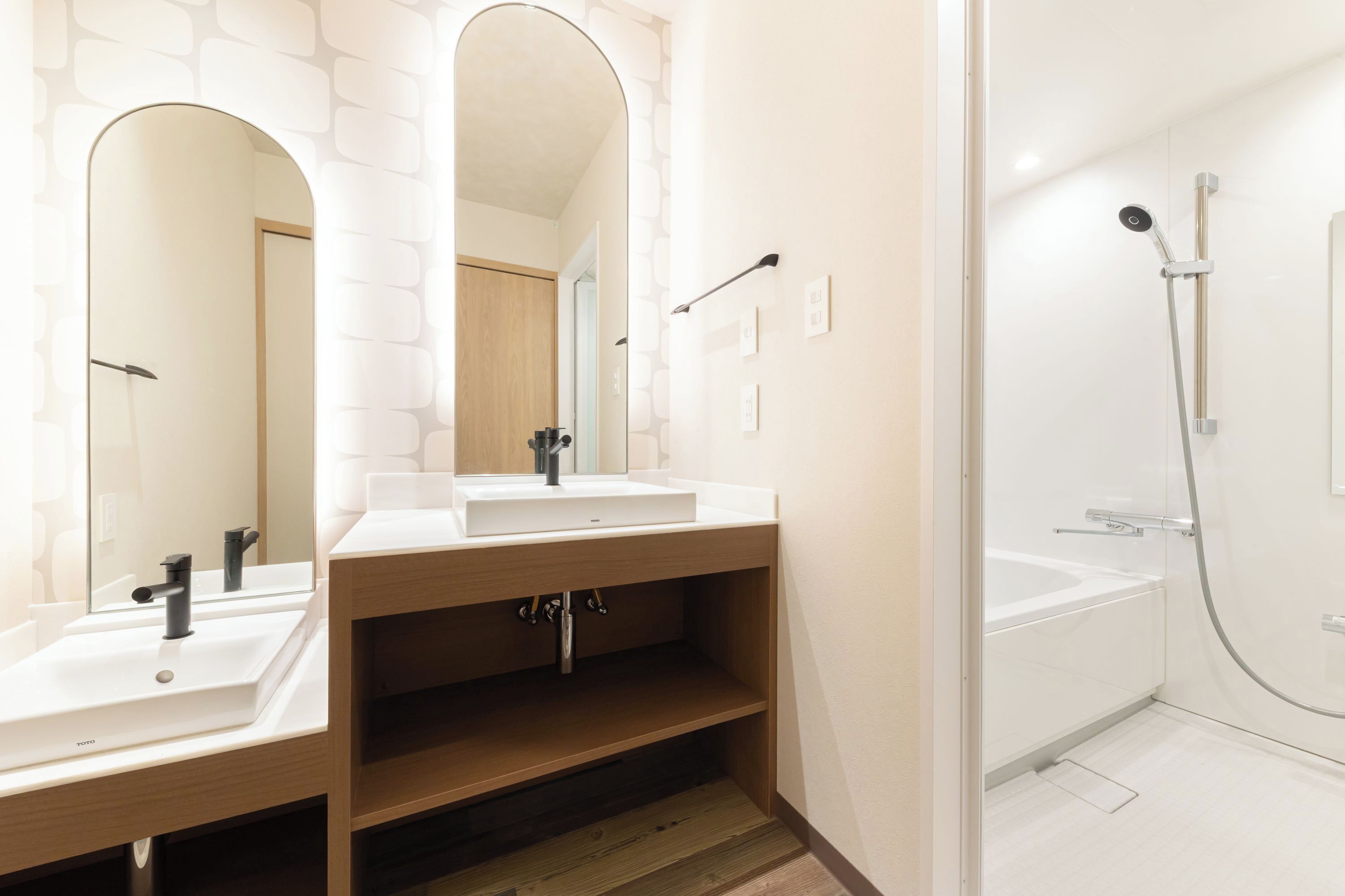 Un bagno moderno con due lavabi, uno specchio e una doccia.